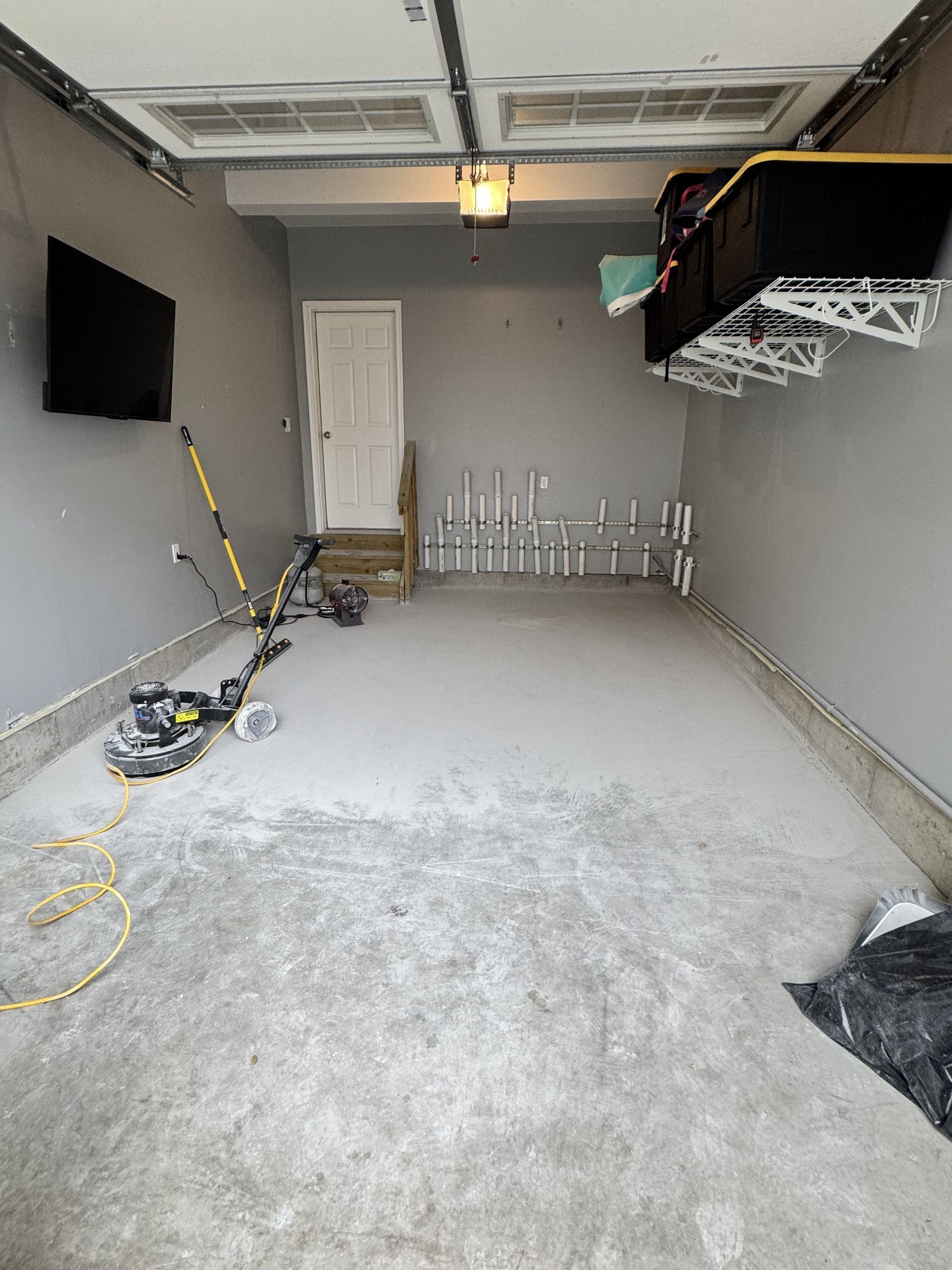 Before: one-car garage with the bare concrete slab being ground, floor grinder on the slab